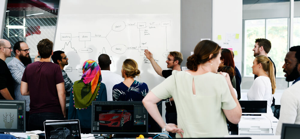 A team discussing work in front of a whiteboard