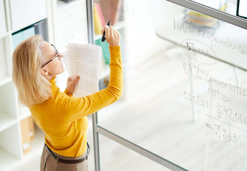 A woman writing on an office glass board