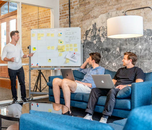 Colleagues collaborating with the aid of a whiteboard with Kanban-style sticky notes