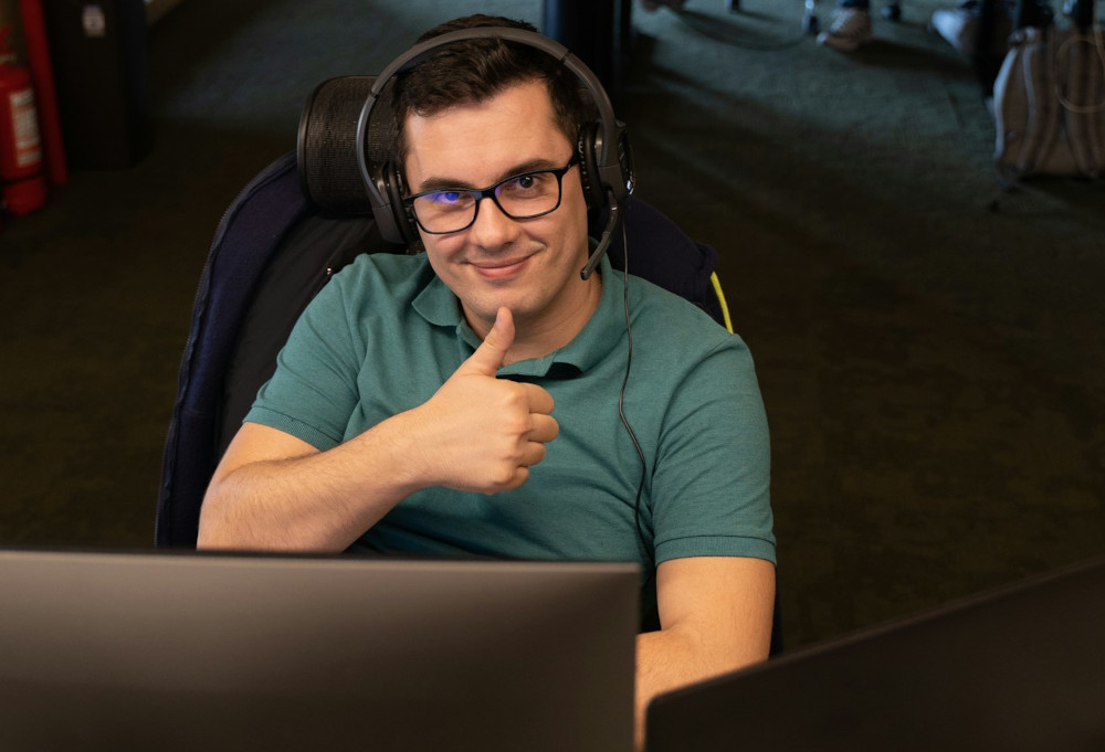 A man at his desk appears satisfied and calm while doing a thumbs-up