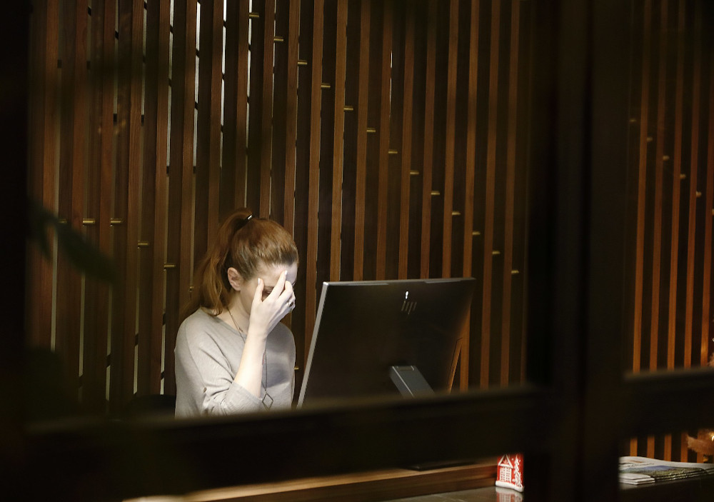 Woman appears stressed-out sitting at her desk in the office