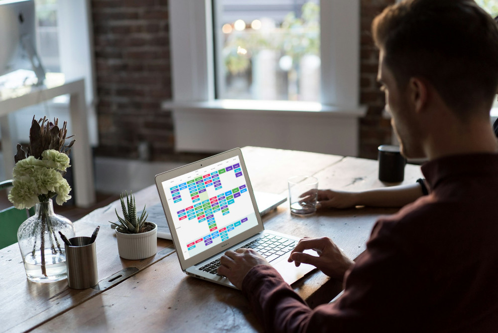 A man working with a Kanban Tool board viewed on a laptop