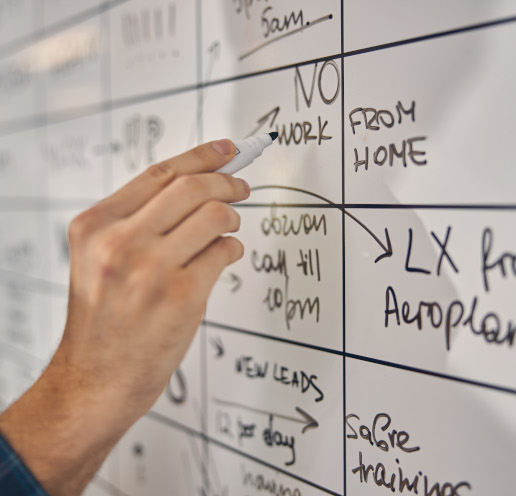 A man wrtiting updates on an office whiteboard