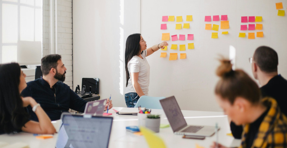 A team leader talks in front of an office Kanban board