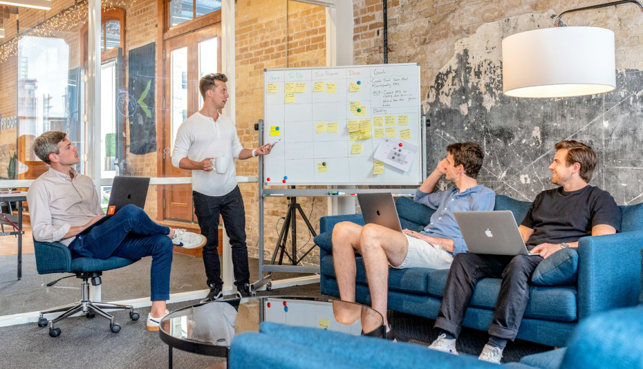 4 team members discuss work with the aid of a Scrum whiteboard