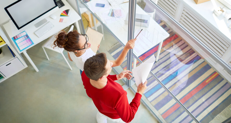 A couple of teammates looking at a progress chart in an office